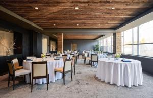 uma sala de jantar com mesas e cadeiras brancas em The Watershed - Formerly Hotel Zero Degrees em Norwalk