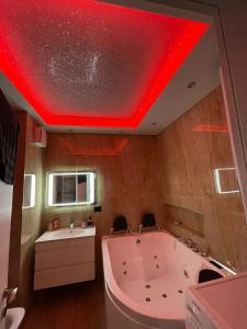 uma grande banheira numa casa de banho com um tecto vermelho em Luxury apartment em Tirana