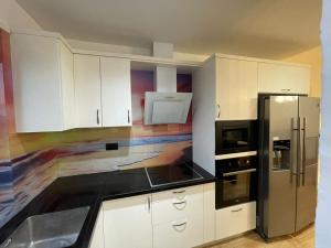 uma cozinha com armários brancos e um frigorífico preto em Luxury apartment em Tirana