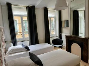 2 łóżka w pokoju z kominkiem i lustrem w obiekcie Les Suites de l'Enclos - L'Enclos de l'Evêché w mieście Boulogne-sur-Mer