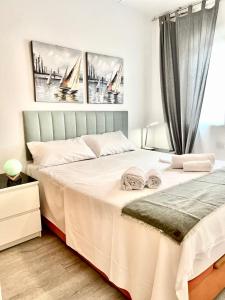 een slaapkamer met een bed met witte lakens en een raam bij El mundo soleado in Santa Pola