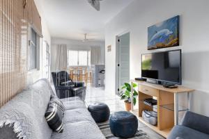 uma sala de estar com um sofá e uma televisão de ecrã plano em Casa da Mole Vista Cond Fechado Paraíso WIFI 250mb em Florianópolis