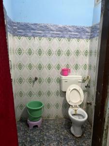 a bathroom with a toilet and a green bucket at Hotel Matushri Guest House in Mathura