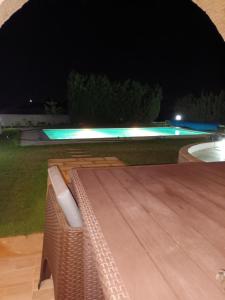 eine nächtliche Aussicht auf einen Pool mit einer Bank in der Unterkunft magnifique villa avec piscine in Dawwār al Frinine