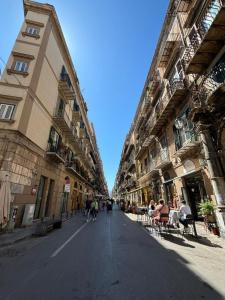 パレルモにあるCasa di Cocòの椅子に座る人々や建物が並ぶ空き街道