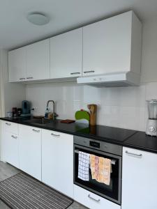 Hello Noordwijk - Zomerhuis Toekomststraat 8 في نوردفايك أن زي: مطبخ فيه دواليب بيضاء وفرن