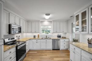 une cuisine blanche avec des armoires blanches et du parquet dans l'établissement Southern Mermaid Cottage- Pet Friendly Fenced, à Saint Joe Beach