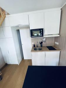a small kitchen with white cabinets and a microwave at Tiny House en lisière de forêt in Les Mages