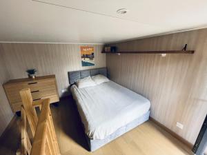 a small bedroom with a bed and a wooden dresser at Tiny House en lisière de forêt in Les Mages