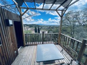 a balcony with a bench on a wooden deck at Tiny House en lisière de forêt in Les Mages