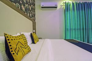 a bedroom with a bed with yellow and blue pillows at SPOT ON Hotel White Rose in Zirakpur