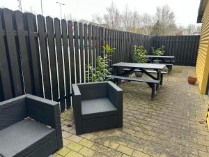 une terrasse avec deux bancs, une table de pique-nique et une clôture dans l'établissement Det gamle snedkeri, à Ribe