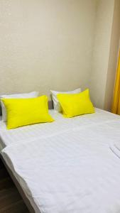 Una cama con dos almohadas amarillas encima. en Нарэл en Bishkek