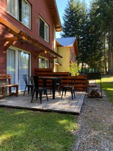 a wooden deck with a table and chairs next to a house at BOG Apart Foresta - A minutos del cerro bayo in Villa La Angostura