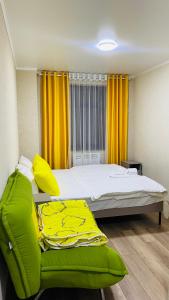 1 dormitorio con 1 cama y 1 silla verde en Нарэл en Bishkek