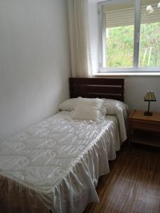 a bedroom with a white bed with a window at VUT El Refugio in Villablino