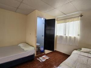 a small room with two beds and a bathroom at Hostal Carolinas in Juayúa