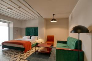 een slaapkamer met een bed, een bank en een stoel bij Manifest Restaurant and Hotel Gyumri in Gjoemri