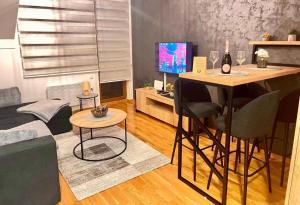uma sala de estar com um sofá e uma mesa com uma televisão em Lux Apartman Aleksandar em Zlatibor