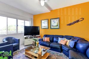 uma sala de estar com um sofá azul e uma televisão em Casa da Mole Praia Particular Churrasco wifi 250mb em Florianópolis
