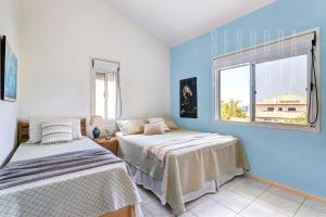 two beds in a room with a window at Casa da Mole Praia Particular Churrasco wifi 250mb in Florianópolis