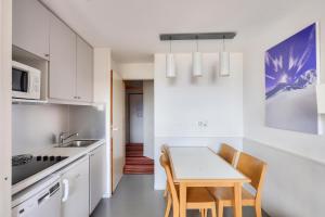 une cuisine avec des armoires blanches et une table et des chaises dans l'établissement Résidence Quartier Falaise - maeva Home - Studio 5 personnes - Confort MAE-0504, à Avoriaz 17 autres photos