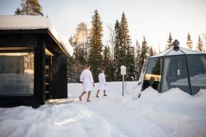 two people in white standing in the snow next to a van at Nova Galaxy Village in Rovaniemi