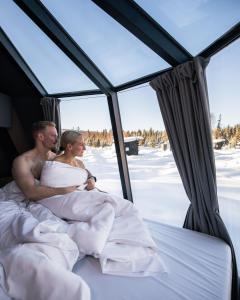 una sposa e uno sposo stesi a letto nella neve di Nova Galaxy Village a Rovaniemi