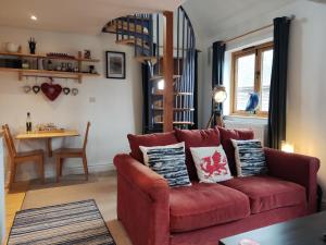 a living room with a red couch and a table at The Studio, Upper House Farm, Crickhowell with Double Garage and Free Parking in Crickhowell