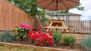 um jardim com um guarda-sol, uma mesa e flores em Mini hotel with home facilities in Hamilton West em High Blantyre
