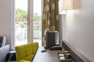 グラディニャンにあるLogis Hotel Restaurant & SPA Au Comte d'Ornonのテレビ、デスク、黄色い椅子が備わる客室です。