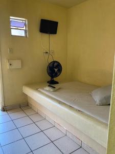 a room with a bed with a fan and a television at Pousada Caliente in Maceió
