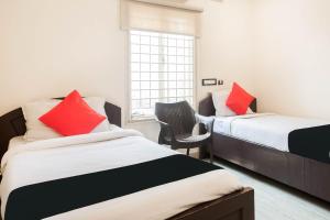 a bedroom with two beds with red pillows and a window at Hotel Aditya Grand in Guntūr