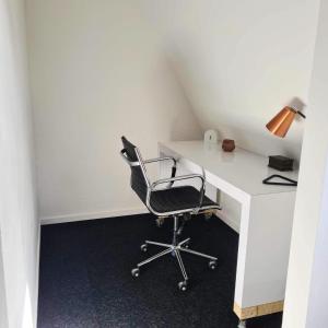 ein Büro mit einem Stuhl und einem Schreibtisch mit einer Lampe in der Unterkunft Horyzont in Noordwijkerhout