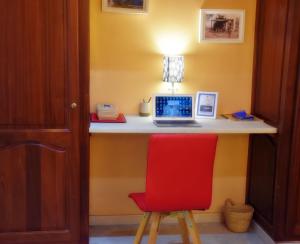 een bureau met een laptop en een rode stoel bij Confort et tradition au coeur de la ville - Faire demande de réservation - in El Jadida