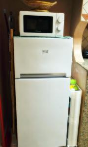 a microwave sitting on top of a refrigerator at A 2 pas de la plage, appartement cosy, confort, proche toutes commodités, Wifi haut débit, TV connectée, Netflix, climatiseur, Acte mariage pour couple national,3 nuits mimum in El Jadida
