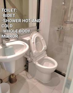 a bathroom with a toilet and a shower hot and cold whole body mirror at SM Bicutan Condominium in Manila