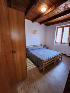 een slaapkamer met een bed in een kamer met een deur bij Casa vacanza a Forno di Valstrona con terrazzo e giardino in Strona