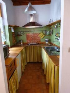 een keuken met een lang aanrecht met gele gordijnen bij Casa vacanza a Forno di Valstrona con terrazzo e giardino in Strona