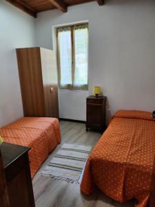 een hotelkamer met 2 bedden en een raam bij Casa vacanza a Forno di Valstrona con terrazzo e giardino in Strona