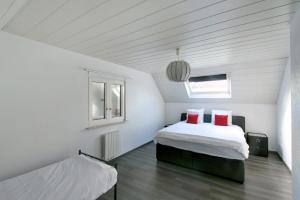 2 camas en una habitación con paredes blancas y almohadas rojas en Chez Mado, en Hatten