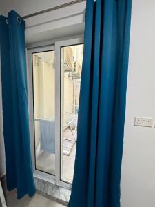 una ventana con cortinas azules en una habitación en Private Room in Beatifull Aparment en Birkirkara