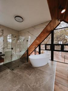 La salle de bains est pourvue d'une baignoire et d'une douche en verre. dans l'établissement La Forêt Cabañas Boutique, à León