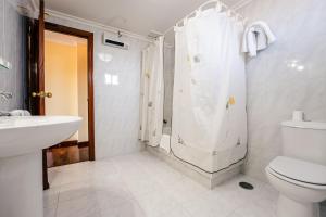 a white bathroom with a toilet and a shower at Hotel Restaurante GBC Isape in Arcade