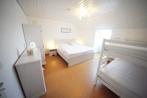 a white bedroom with a bed and a refrigerator at Berg-Juwel mit Pool und Sauna für Familien und Hunde ideal in Missen-Wilhams