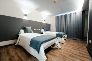 two beds in a room with wooden floors at Hotel Restaurante GBC Isape in Arcade