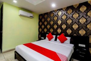 a bedroom with a large bed with red pillows at Capital O Swan Paradise in Indore