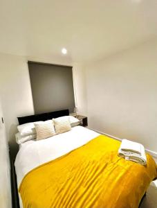 1 dormitorio con 1 cama grande con manta amarilla en The Light House en Londres