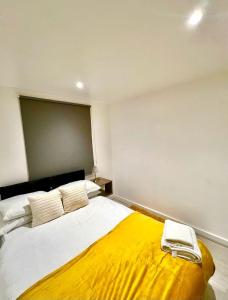 1 dormitorio con 1 cama grande con manta amarilla en The Light House en Londres