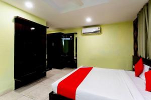a bedroom with a bed with a red and white blanket at Capital O Swan Paradise in Indore